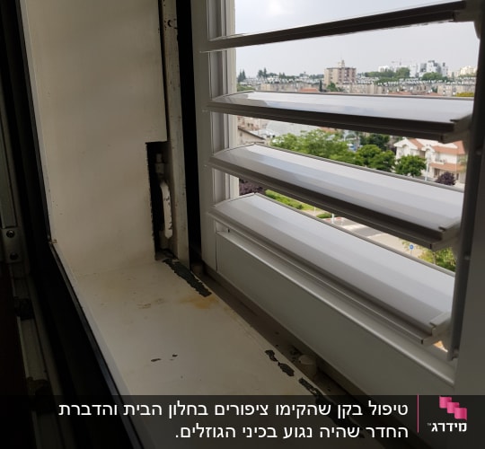 חלון פתוח עם סימני חלודה על אדן החלון